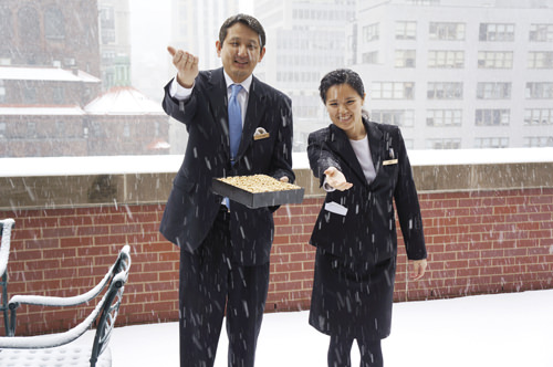 降りしきる雪の中、同ホテルルーフトップの庭で無病息災と幸福を祈って豆をまく小島恭之副総支配人（左）とスタッフ＝３日、ニューヨーク（撮影：池浦）
