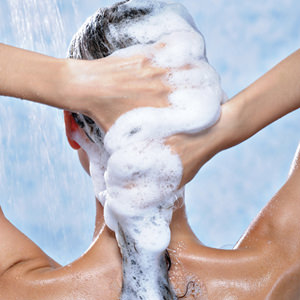 washing long brunette female hair by shampoo