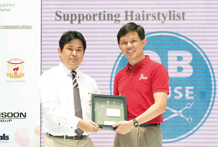 シンガポールで開催された、小児がん患者を勇気付ける「HAIR FOR HOPE」のイベントで感謝状を渡されるQBHOUSE　ＵＳＡ社長の古谷亮二さん（左）