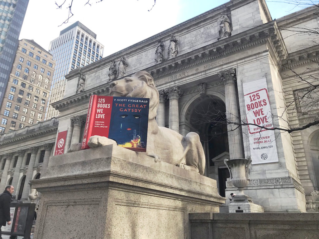 NYPL本館前の２体のライオン像には「私たちが愛する125冊」にちなんだ飾りがされた。写真は、Ｆ・スコット・フィッツジェラルド作『グレート・ギャツビー（原題：The Great Gatsby）』を読むような飾りがされた「フォーティテュード（Fortitude）」。向かって左側の「ペイシェンス（Patience）」はトニー・モリスン作の歴史小説『ビラヴド（原題：Beloved）』を“読書中”＝19日、ニューヨーク（撮影：田部井）
