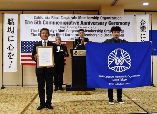 リトル東京倫理法人会の認可書と行動旗を掲げる、本庄修会長（左）と尾崎泰斗専任幹事