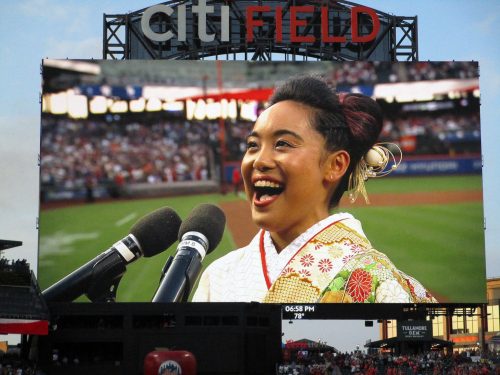 フィールドの大型スクリーンに映し出された前嶋利菜さんの米国国歌独唱＝８月25日、ニューヨーク