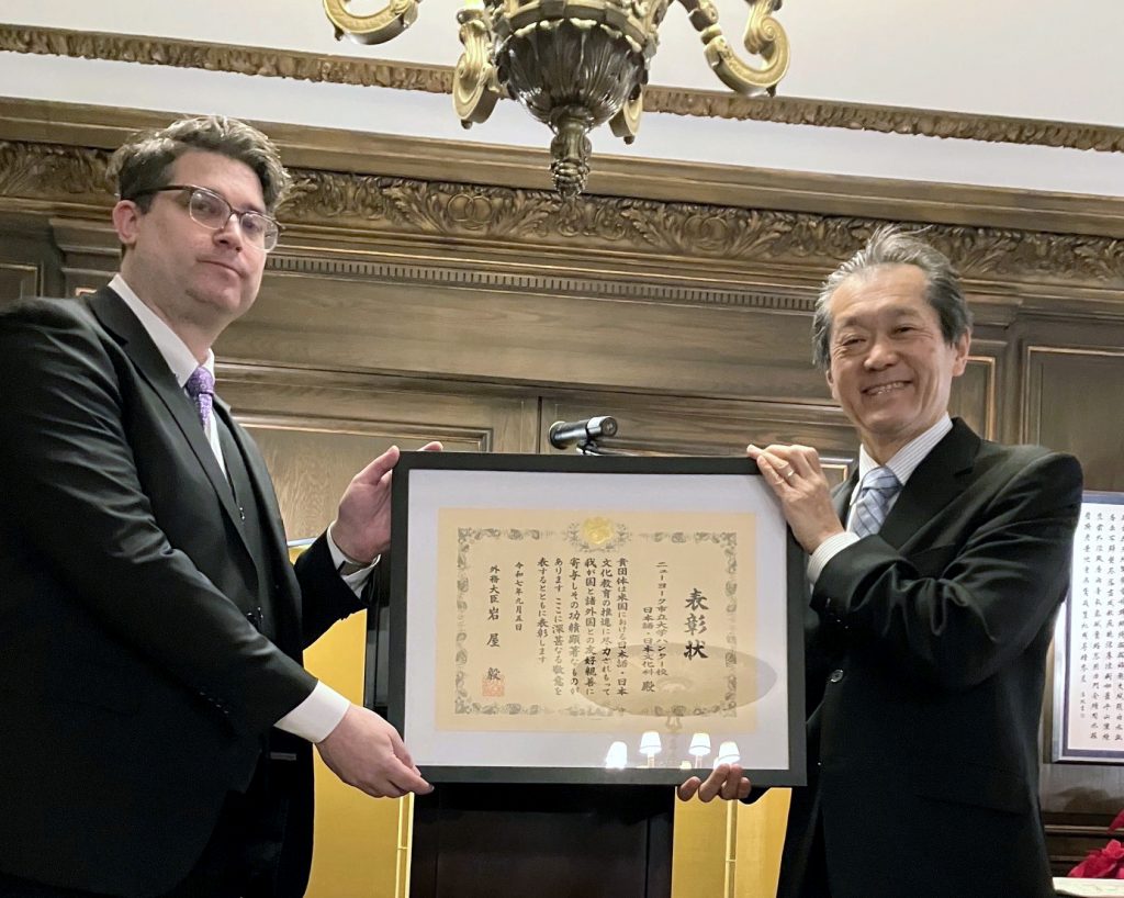 片平聡ニューヨーク総領事・大使からアレックス・ロガルズ暫定課長に表彰状が授与された＝12月８日、ニューヨーク