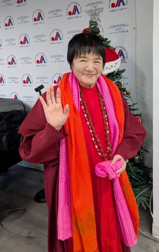 会場の参加者に手を振るヨグマタ相川圭子氏＝12月20日、ニューヨーク