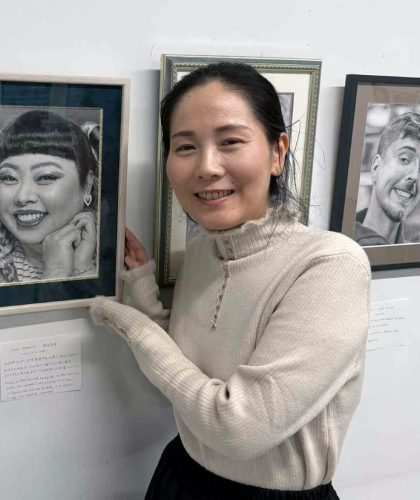 自身の作品の前に立つ岡崎久美子さん